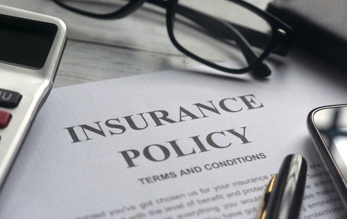 Life insurance policy document with glasses and calculator